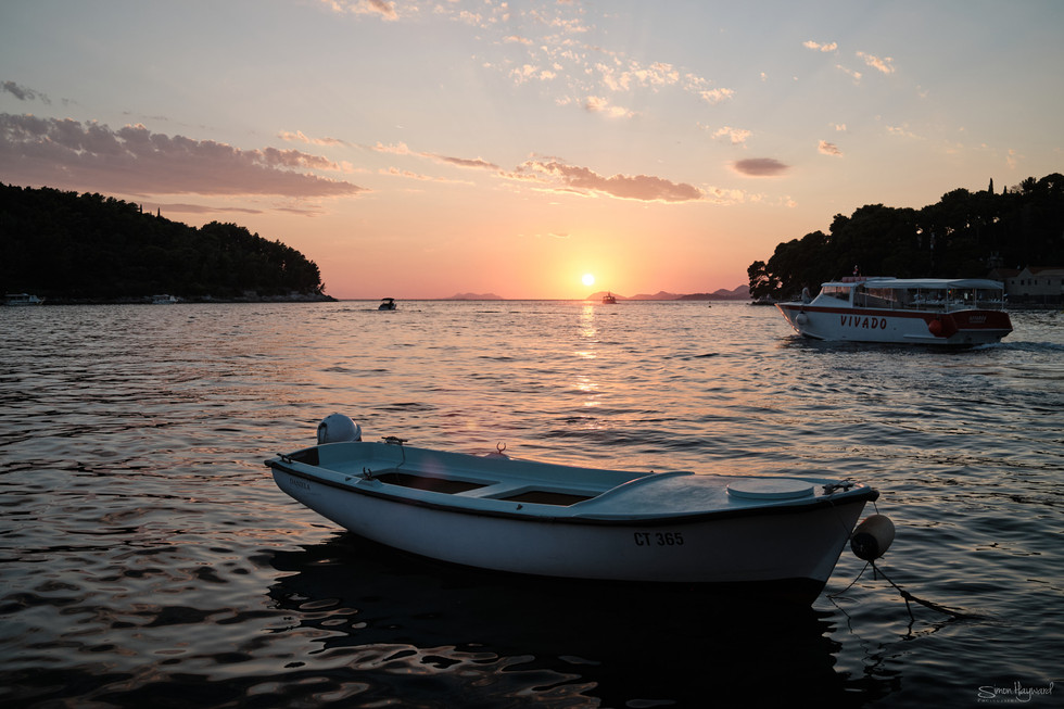 Sun setting on horizon with boat in foreground
