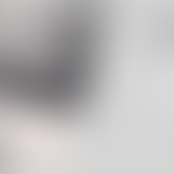 Zwart-witfoto van een jonge vrouw die nadenkend voor zich uit kijkt met een koffiebeker in de hand, op een terrasje in de stad.