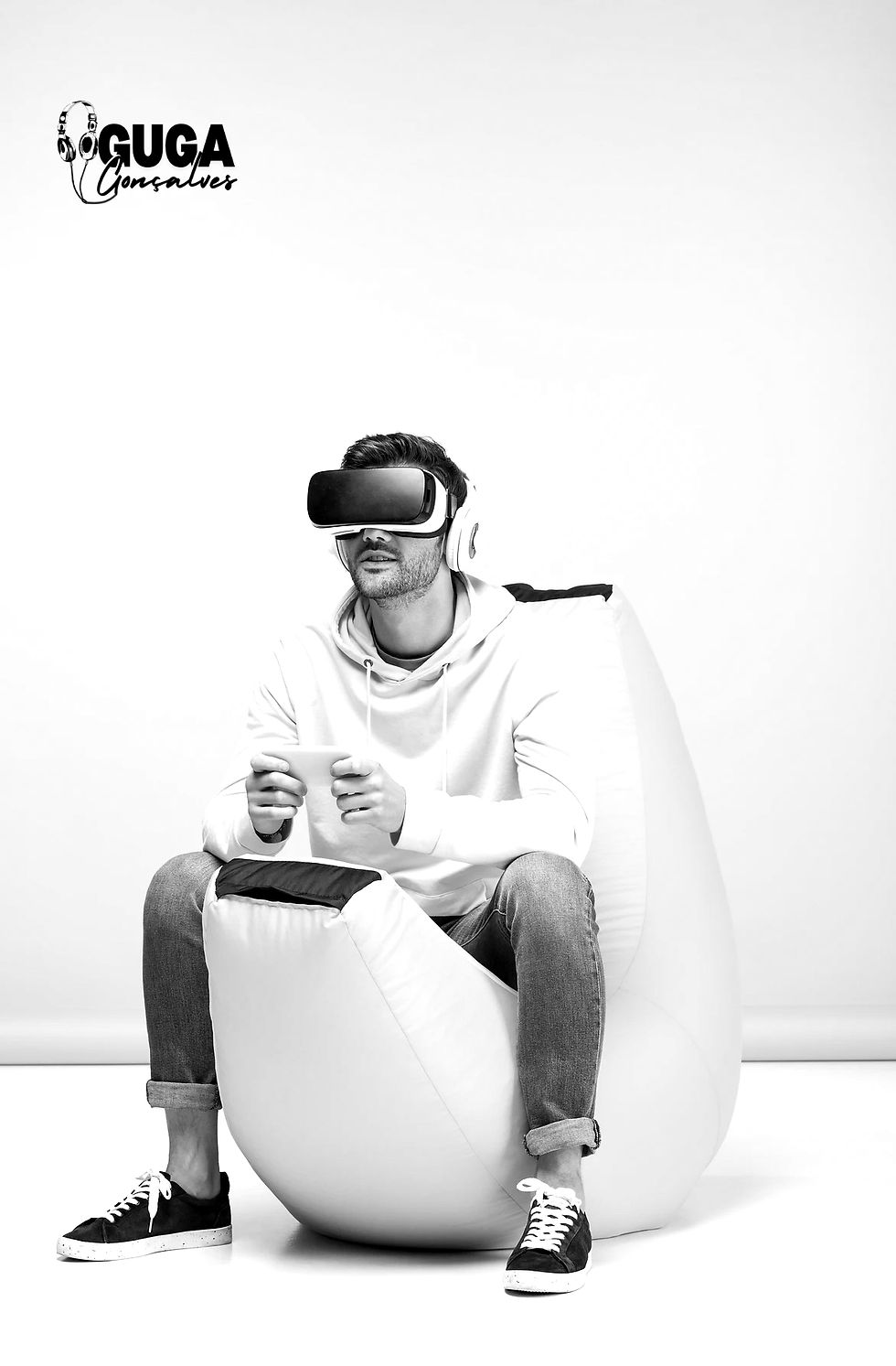 foto de um rapaz sentado num pufe, jogando com um joystick em mãos e um óculos de realidade virtual 