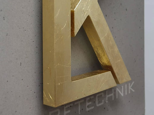 Exklusives Firmenlogo aus Edelstahl, montiert auf einer grünen Echtmoos-Wand, gefertigt von LK Werbetechnik.