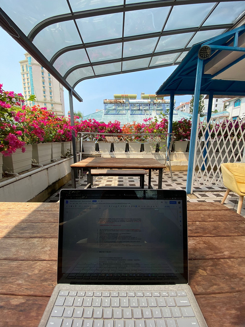 laptop on a table with flowers in the backdrop