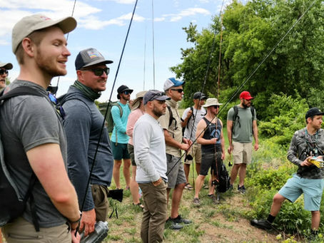 group of new anglers gather by the river for instruction on fly fishing