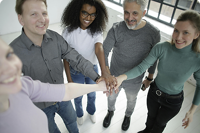 Group of people in a professional setting joining hands by collaborating together