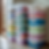Stacked labeled plastic bins in various colors, sorted by season and clothing type, placed on a tiled floor near wooden-framed windows.