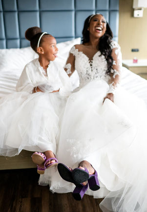 bride and flower girl laughing on bed