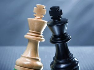 two chess kings, one white and one black, facing off close together on a board