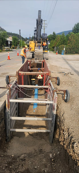 Excavator digging deep trench for Kelowna water main install