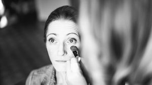 Jesmond Dene House wedding, Newcastle Upon Tyne. a black and white photo of a woman applying makeup