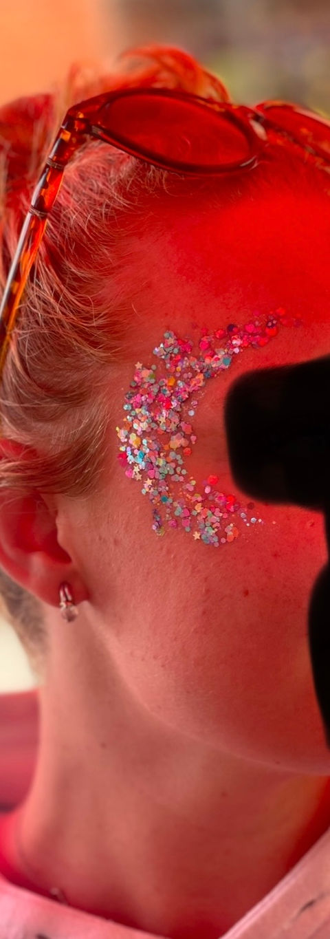 A guest with shimmering festival-style glitter on their face, applied at a professional Glitter Bar.