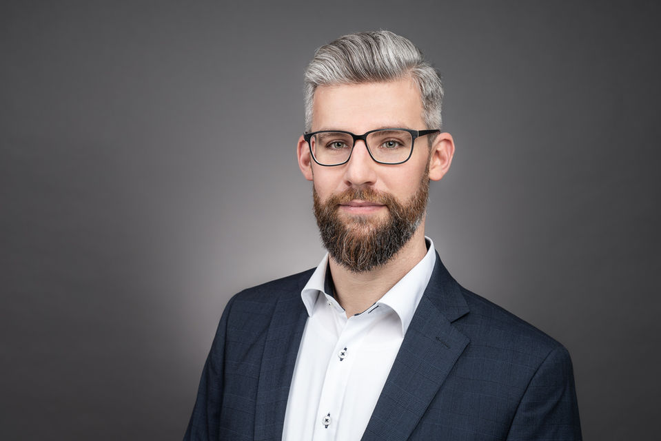 Mann mit Brille und Anzug auf einem Bewerbungsfoto Wien