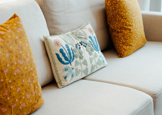 Cream sofa with mustard and embroidered floral cushions, warm modern living room