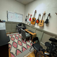 Cozy music room with string instruments, drum kit, and whiteboard.