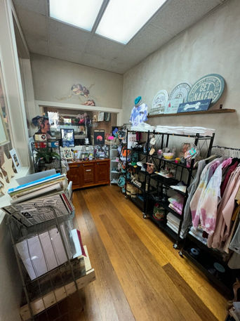 Boutique store interior: wooden floor, shelves with clothes, crafts, and gifts.