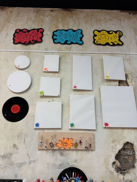 Decorated wall with "VIBES GOOD ONLY" signs, white boards, and vinyl record.