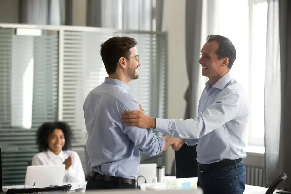 Two men shaking hands and smiling.