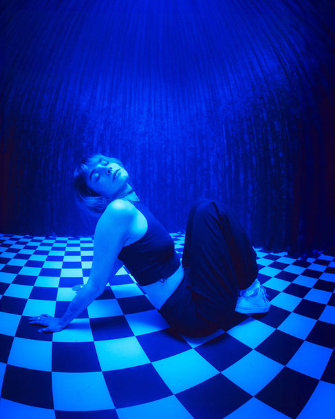 Person im Twin Peaks inspirierten Red Room Set des Mietstudio Halle 7 in Lünen, NRW mit blauer Lichtstimmung, roten Samtvorhängen und Schachbrettboden für kreative Film- und Fotoproduktionen