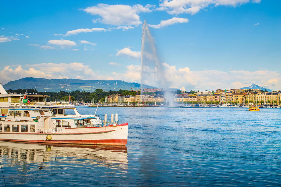 Jet d’Eau water fountain shooting into the sky on a sunny day in Geneva, with Lake Léman and city buildings in the background.