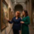Two friends in their 50s looking at a painting in a museum, traveling together
