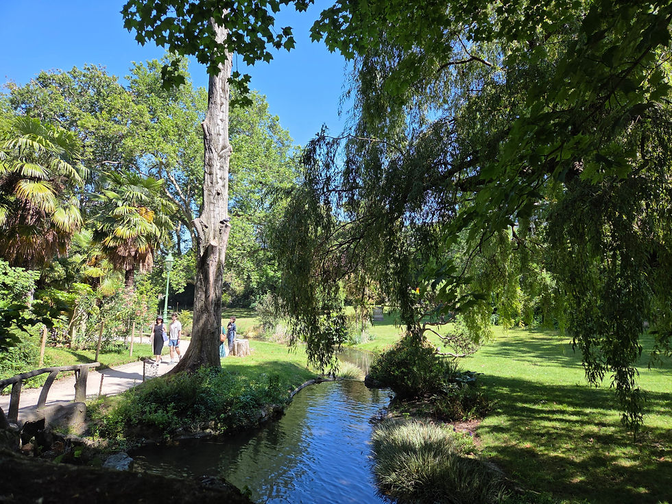Stream, trees, and shaded paths in Square des Batignolles, a quiet garden in the 17th arrondissement of Paris.