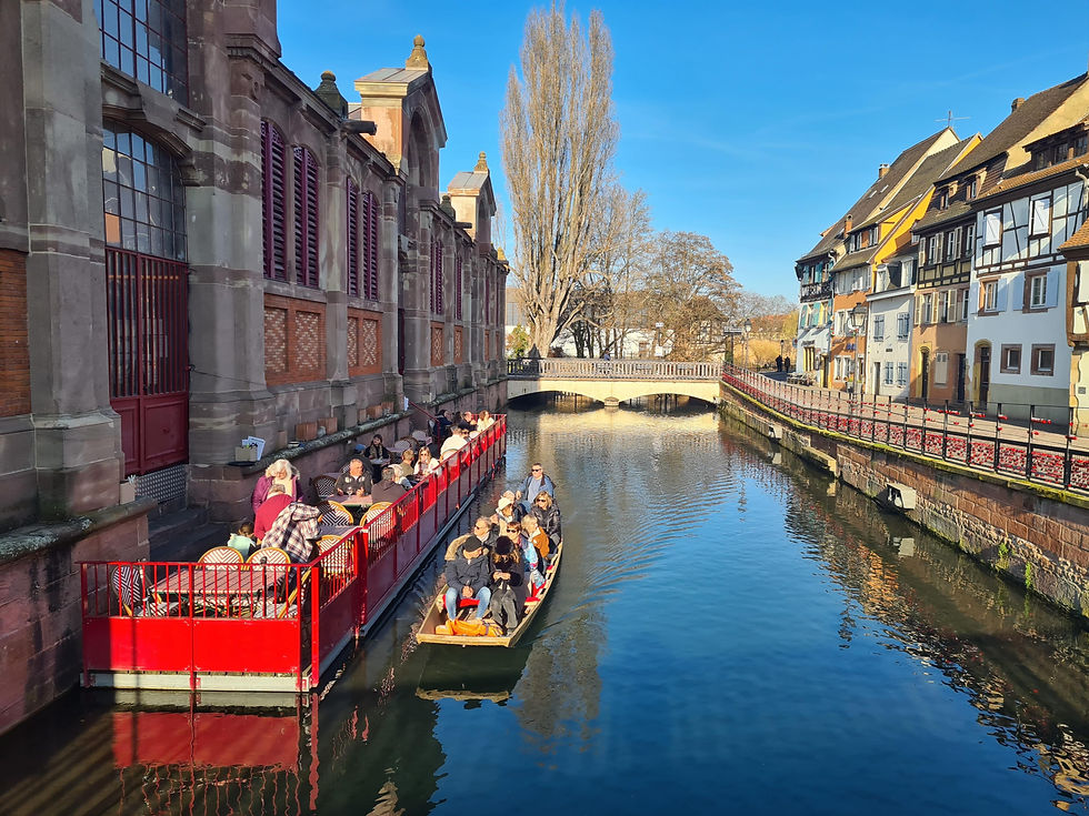 Canal boat passing half-timbered houses along the Lauch river in Colmar, Alsace, France