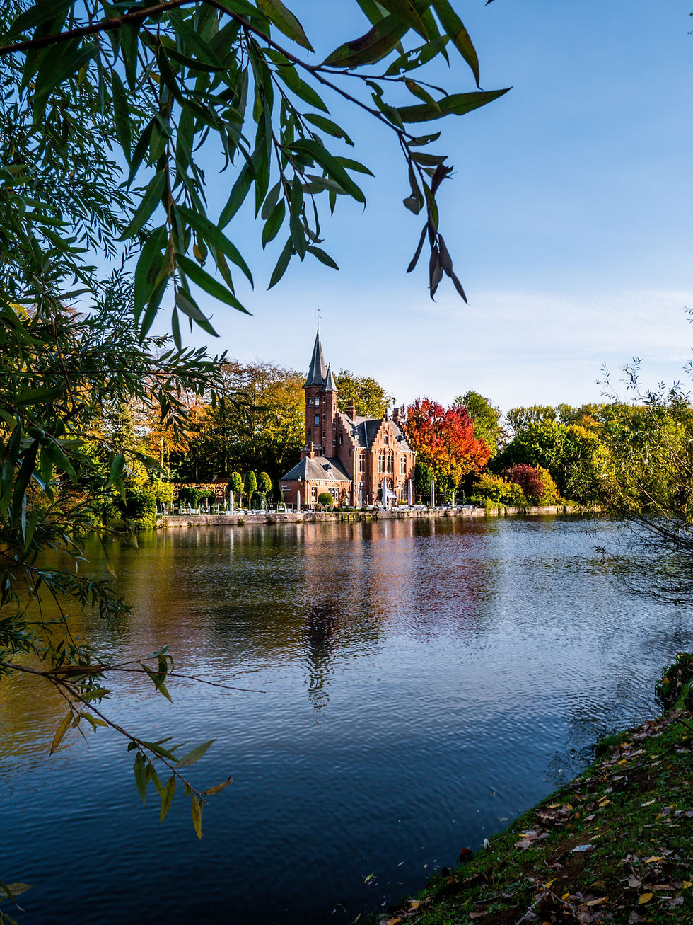 The red-brick neo-Gothic Minnewater Castle reflecting in the calm waters of the Lake of Love in Bruges, Belgium