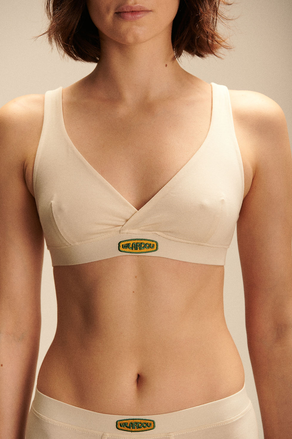 Thumbnail: White oat milk Organic cotton bra with wide non adjustable straps with embroidered logo in the middle of under bust band
