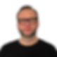 Wojtek with a nice haircut, in strong black glasses is looking at you and sending you a smile