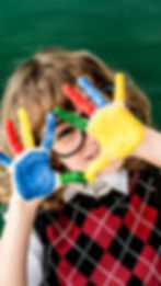 La imagen muestra a un niño disfrutando de actividades escolares con las manos pintadas de colores, reflejando creatividad y bienestar. Esta escena se relaciona con los exámenes médicos escolares, ya que un adecuado control de salud garantiza que los niños puedan participar plenamente en su desarrollo académico, social y artístico sin limitaciones.