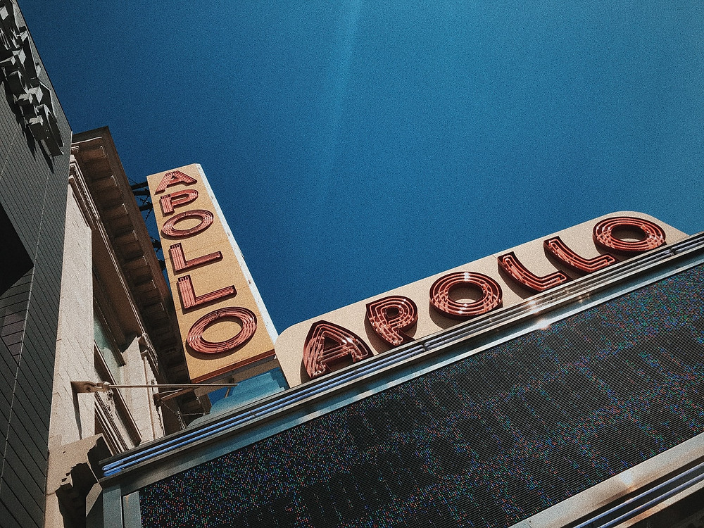 A closeup of the Apollo Theater sign in Harlem, New York City with a blue sky in the background.