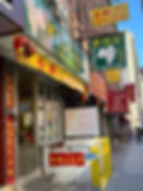 Exterior of 83 Bayard Street with green, yellow, and red signs welcoming into the shop, home to Tonii’s Fresh Rice Noodles in Chinatown NYC.