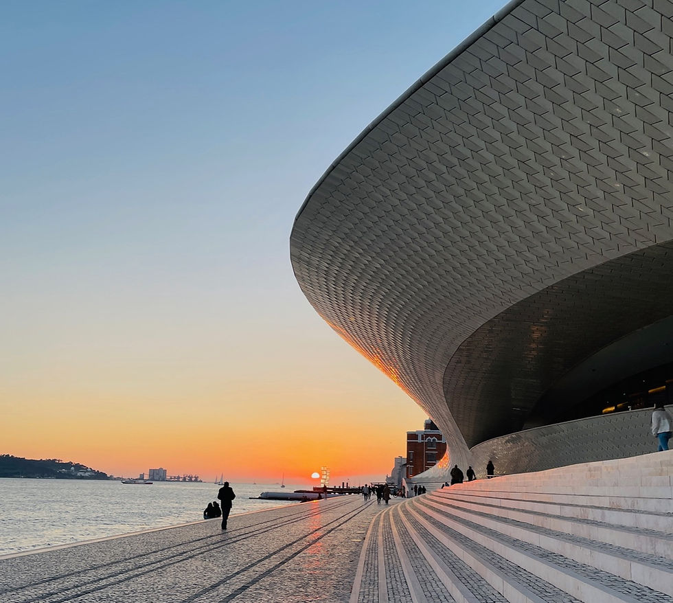 Blue and orange sunset in Lisbon with a white curved building on the right side