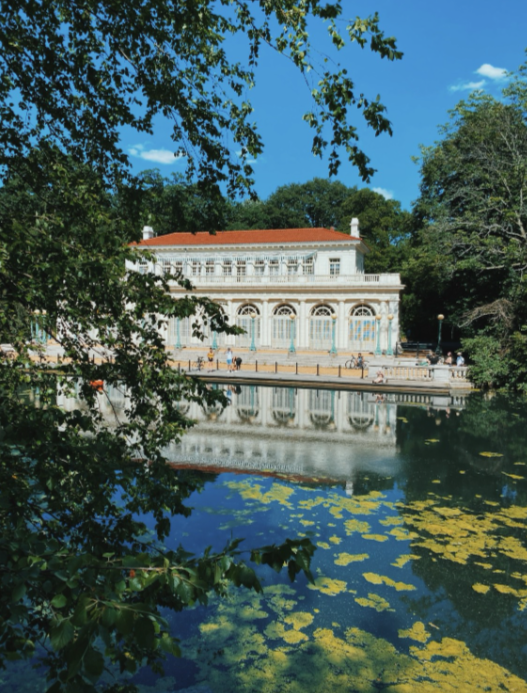 Exterior of the boathouse in Prospect Park Brooklyn. Surrounded by the green trees and pristine blue lake.