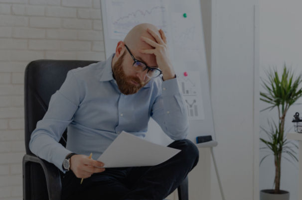 Um homem sentado, lendo um documento com preocupação