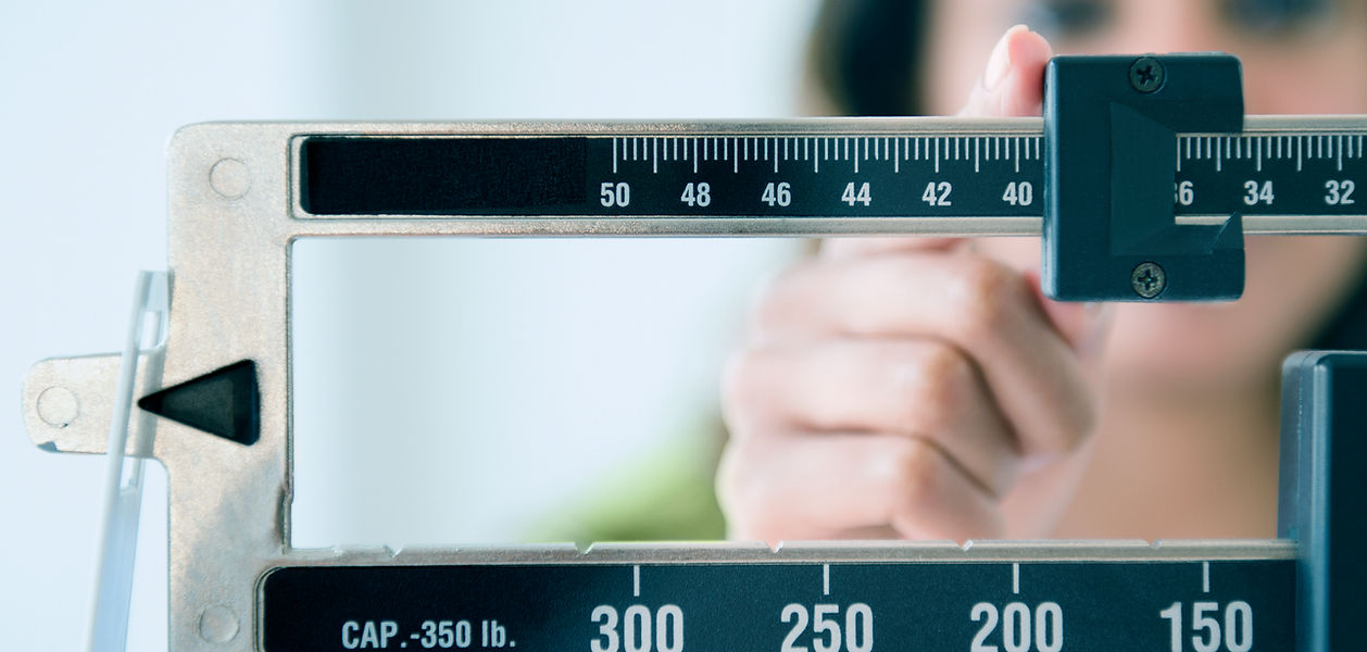 Woman adjusting weight scale after losing weight with PriorityYou Health Center Semaglutide and Tirzepatide