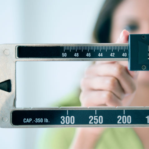 A person adjusting an upright doctor’s office scale.