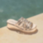 Lifestyle angled view of Caprice Eileen wedge sandal in light gold metallic leather styled for summer we