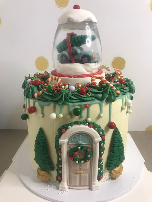 Witte taart in kerstthema met sneeuwglobe en dennengroene decoratie.