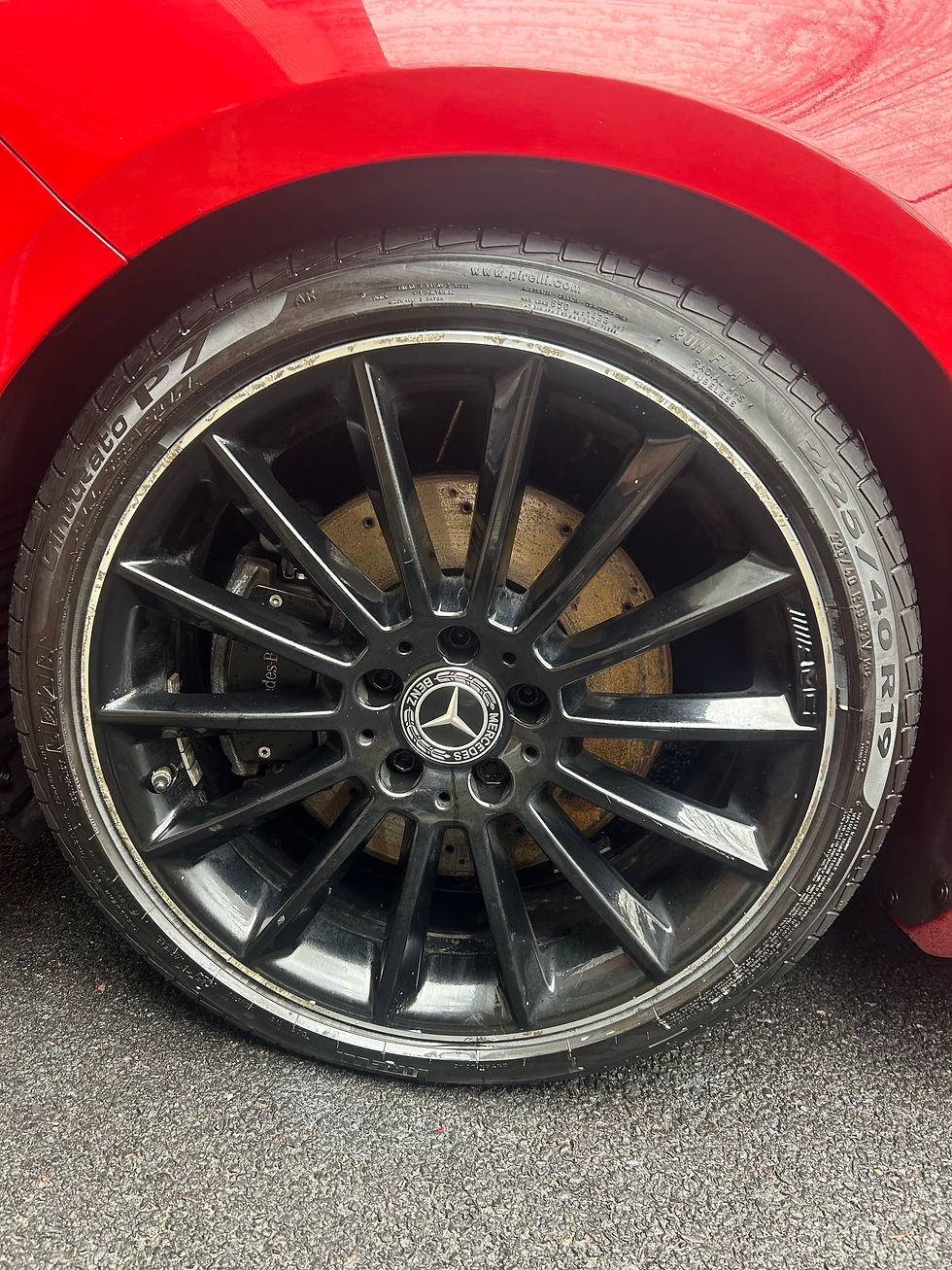 A shiny tire on a red car that has been freshly cleaned.