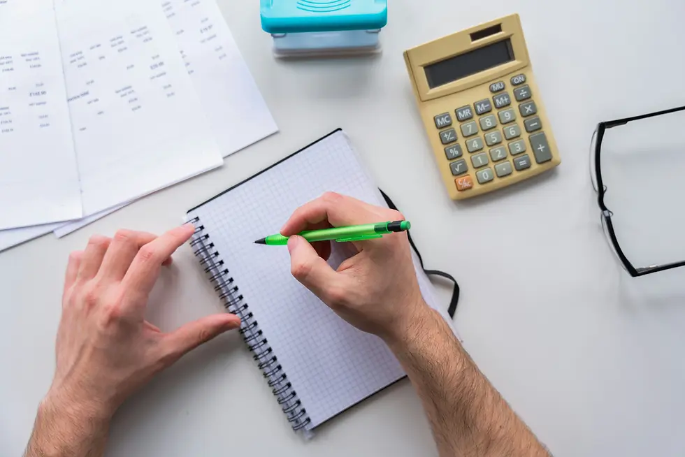 Man writing on a graph paper at a desk with a calculator and other notes