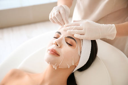 Cosmetologist applying sheet mask on woman's face in beauty salon.jpg