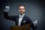 Orchestra conductor with arms raised in the ready positions.