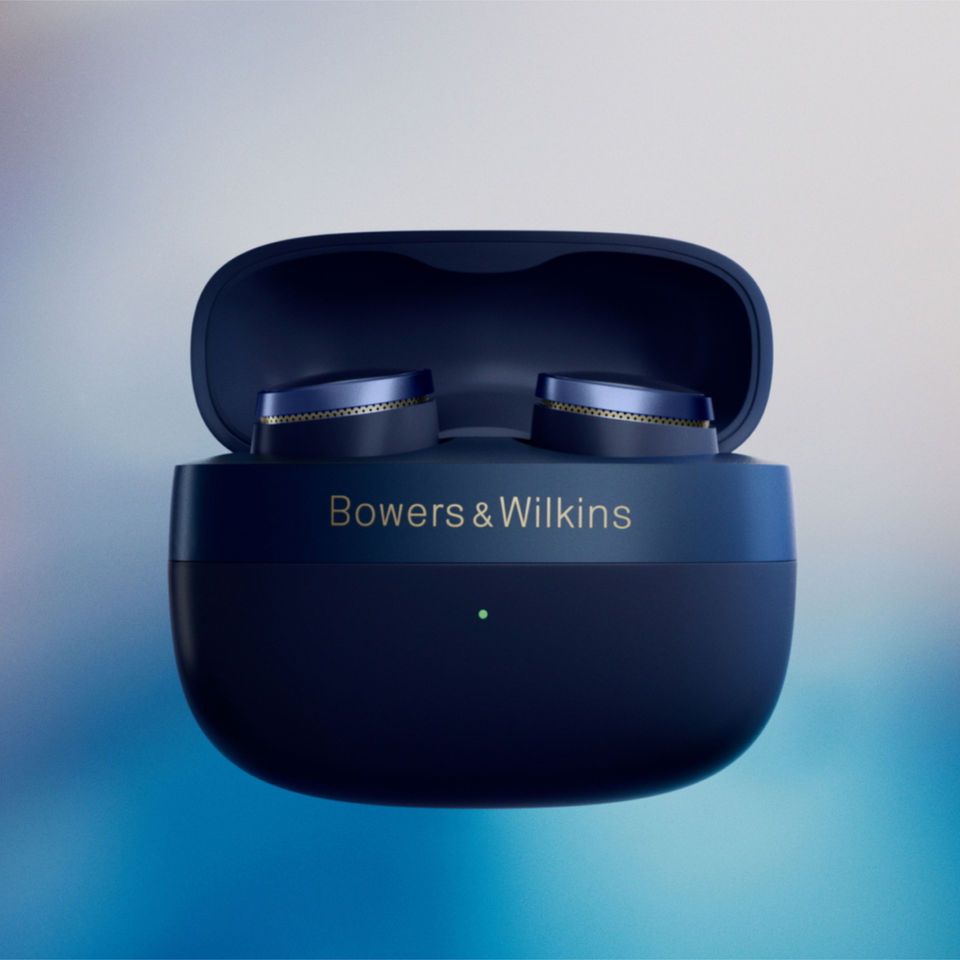 Luxurious Midnight Blue and gold B&W earbuds mounted in the pebble-like charging and storage case