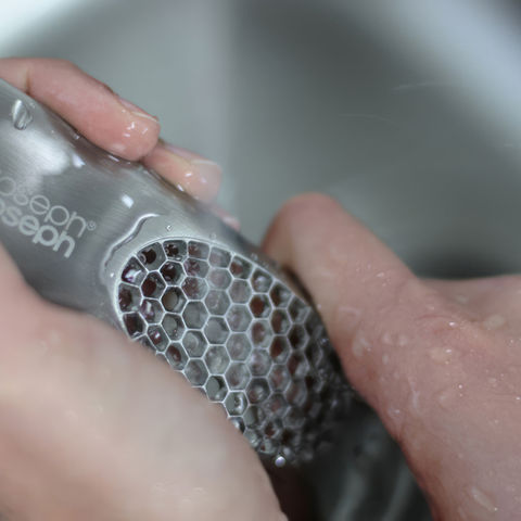 Someone washing the rocker garlic crusher from Joseph Joseph. Click to learn more