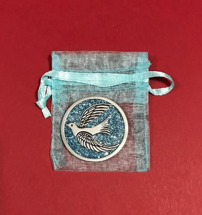 Thumbnail: A blue coin with a dove on it laying on a light blue organza bag.