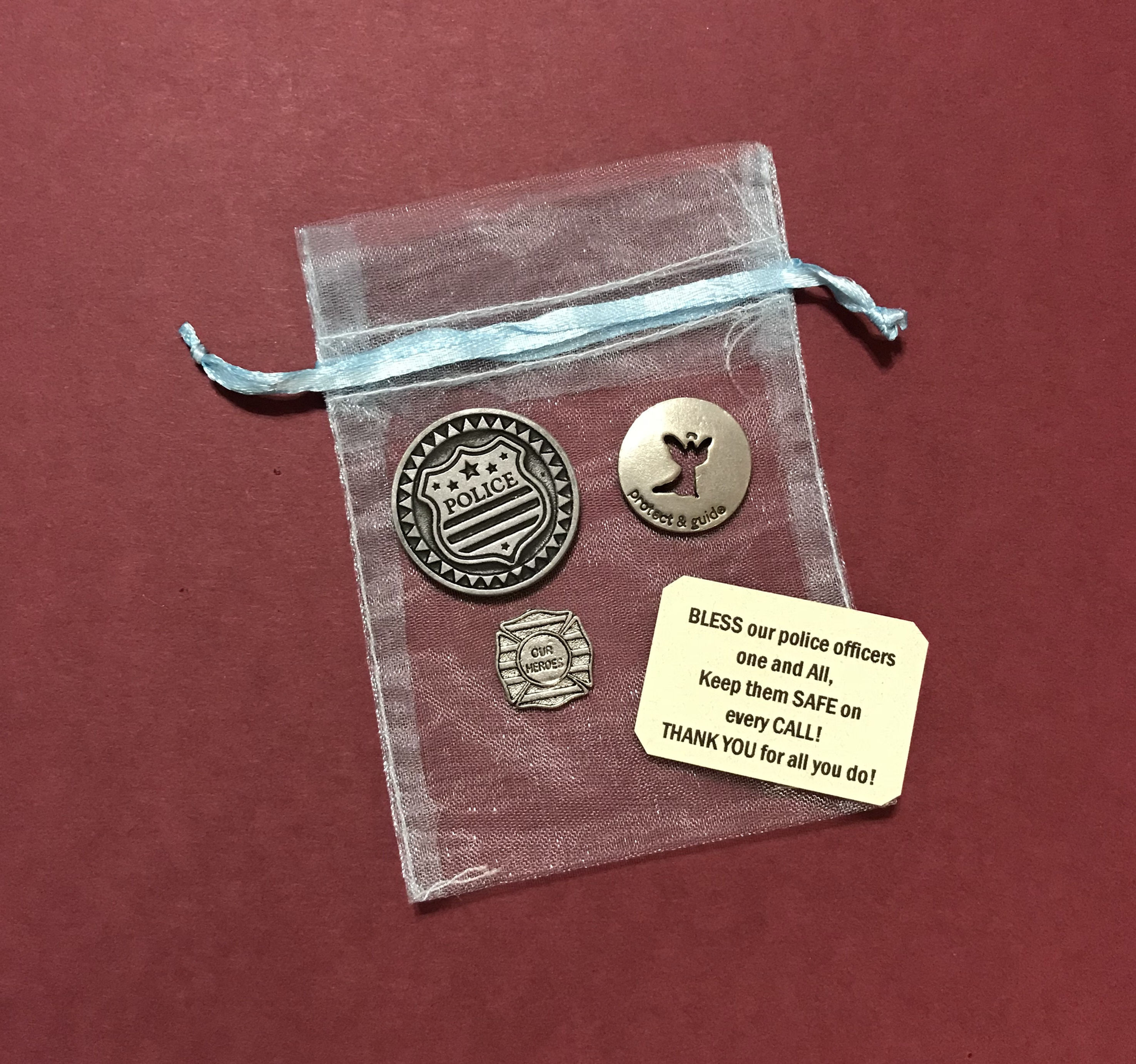 A silver  badge, a silver heart, a circular coin with a quote on each side with a thoughtful card for a policeman and a bag.
