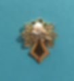 A bright gold delicate angel pin with a pearl head and a silver bow against an aqua background.