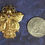 Thumbnail: An exquisite gold angel pin with silver butterfly wings on a navy blue background along side a quarter.