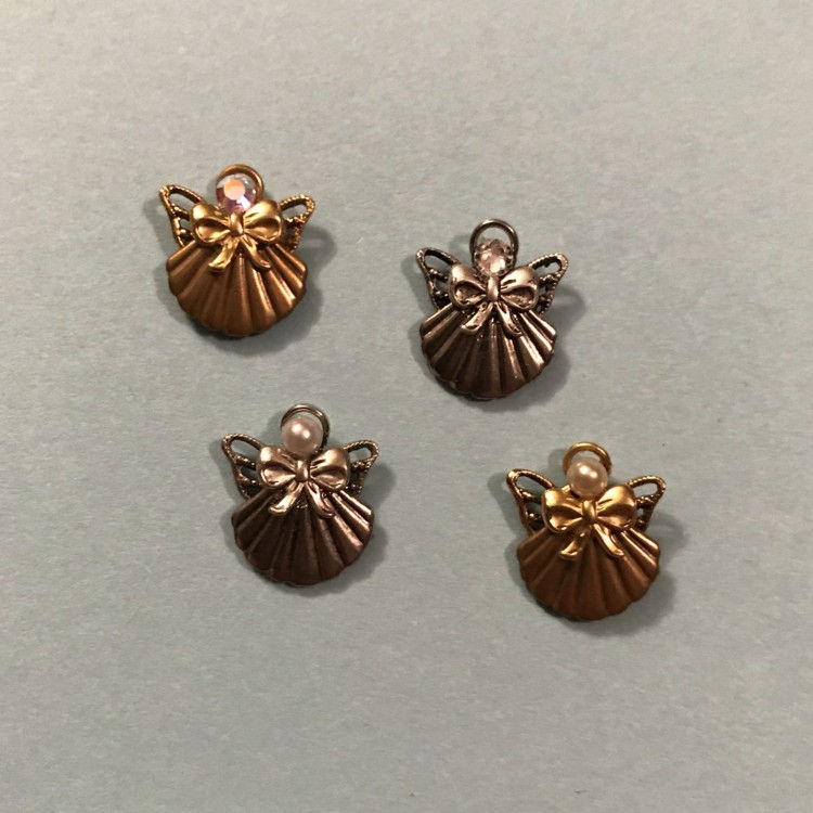 Four little angel pins, two silver, two gold on a pale green background.