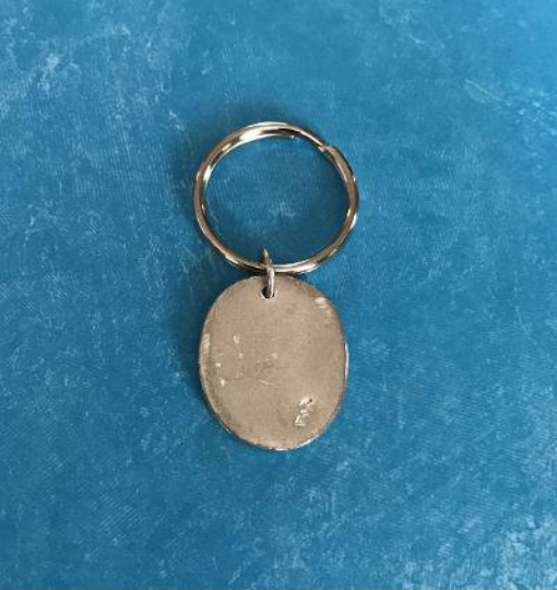 back view of pocket angel key ring on teal background