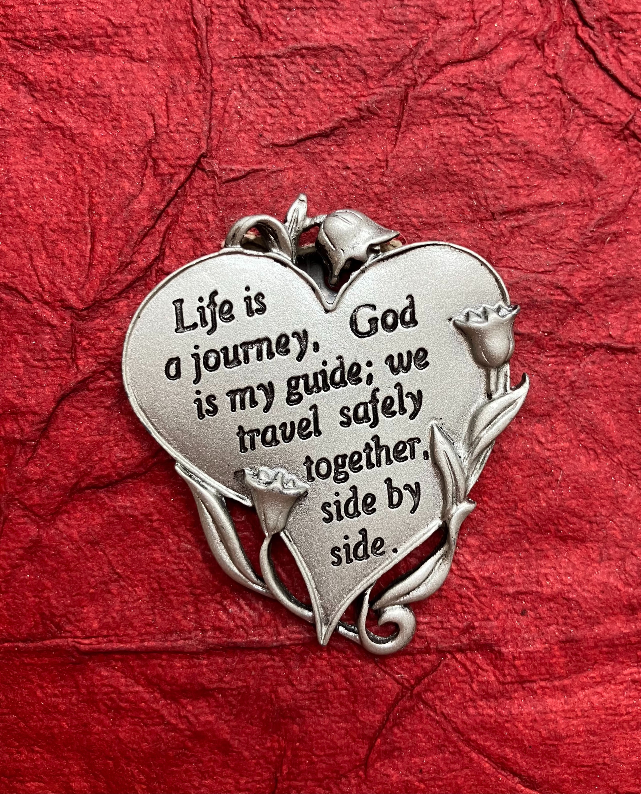 A pewter heart-shaped visor clip featuring an inspirational saying, perfect for adding a personal touch to your vehicle.